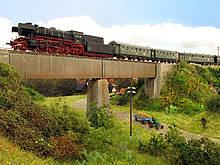 Über das Viadukt auf der Anlage der HEB Hobbyeisenbahner 1983 Rodgau in der Spur H0 fährt eine Dampflok Baureihe 23 mit einem Nahverkehrszug im Stil der 60er Jahre