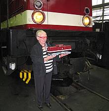 Frau Ortrun D. Wilfer präsentiert den anwesenden Fotografen stolz das PIKO Modell der BR 199 vor der Original-Lok