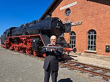 PIKO Geschäftsführer Dr. René F. Wilfer präsentiert das Modell der H0 Dampflokomotive BR 003 vor dem imposanten Original